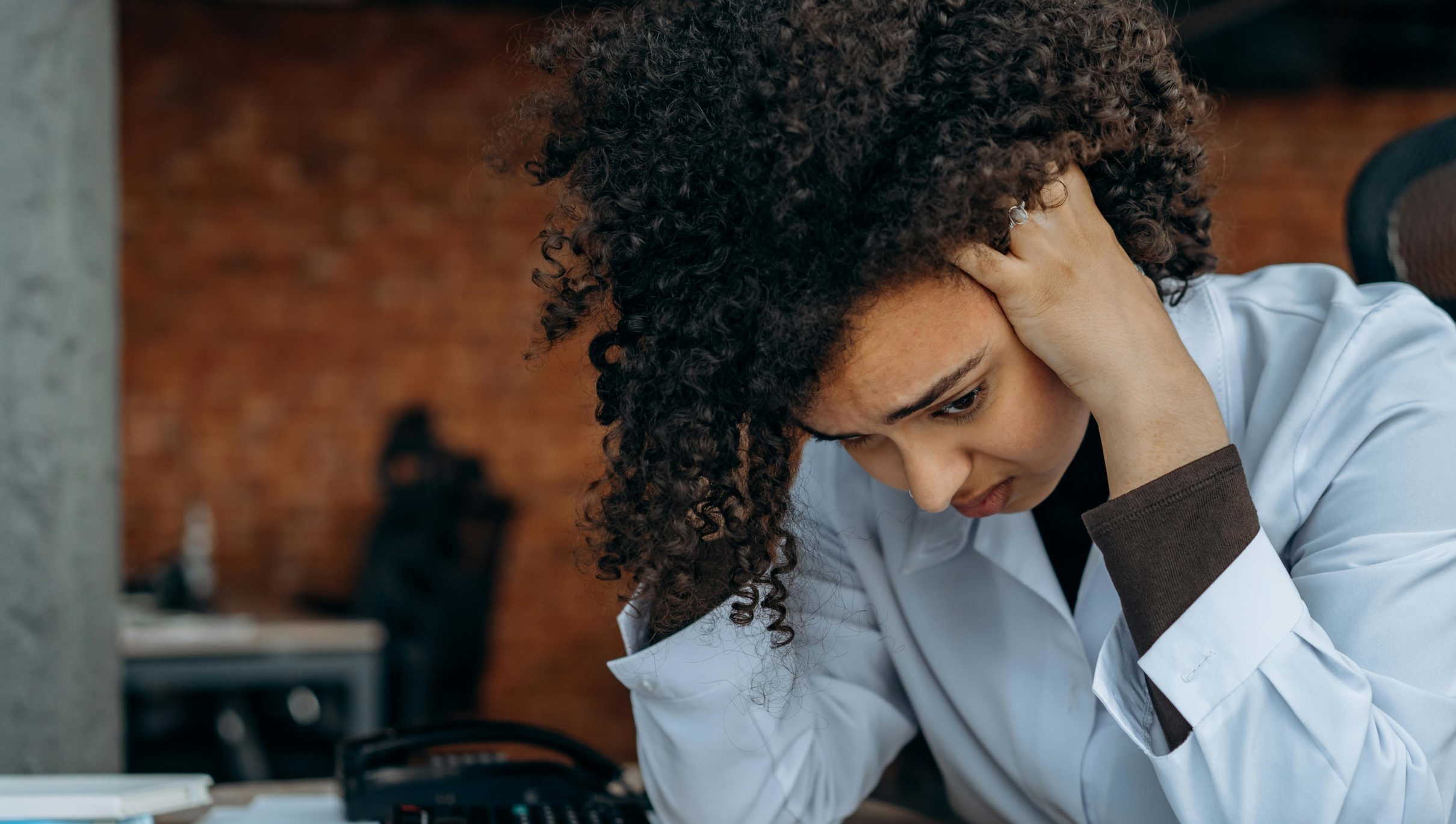 woman at desk with hands on head